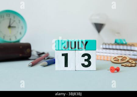 Calendario cubo bianco per luglio decorato con fiori margherita sopra sfondo blu con spazio per la copia Foto Stock