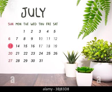 Calendario cubo bianco per luglio decorato con fiori margherita sopra sfondo blu con spazio per la copia Foto Stock