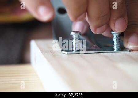 Mani che montano staffe in metallo su una superficie in legno Foto Stock
