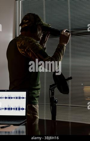 Agente dell'intelligence che conduce la sorveglianza da una stanza chiusa. Concetto di sorveglianza, operazioni speciali, ricognizione Foto Stock
