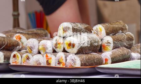 Pile di rotoli di sushi futomaki avvolti in plastica sono esposti su vassoi presso la stalla dell'ambasciata giapponese durante il Festival dell'Ambasciata di Praga, pronti per Foto Stock