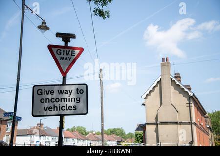 Cartello stradale del Regno Unito con un'avvertenza triangolare "cedere" sopra un cartello con l'indicazione "cedere ai veicoli in avvicinamento", visto a Enfield, Londra. Foto Stock