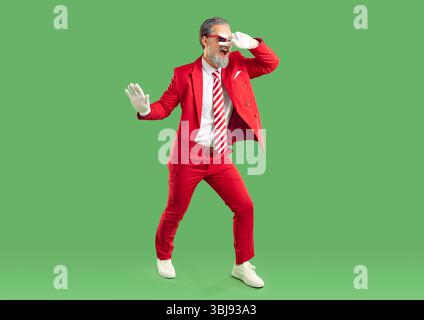 Foto completa di showman allegro e spensierato o presentatore vestito con elegante abito da ballo rosso Foto Stock