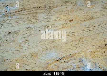Le tracce degli pneumatici sono chiaramente visibili sul terreno sabbioso, mostrando lo schema creato da un veicolo. La superficie sabbiosa indica un ambiente rurale, probabilmente Foto Stock