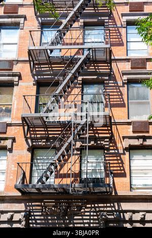Un vecchio edificio di appartamenti in mattoni rossi con scale antincendio. New York, Stati Uniti Foto Stock