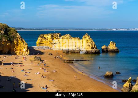 Persone che si rilassano sulla spiaggia Praia de Dona Ana al crepuscolo a Lagos, Algarve, Portogallo. Foto Stock