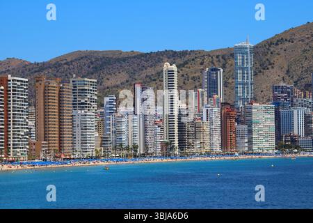 Vista ravvicinata del moderno e alto skyline di Benidorm e di Levante Beach, in Spagna, con acque turchesi e verdi colline sullo sfondo. Foto Stock