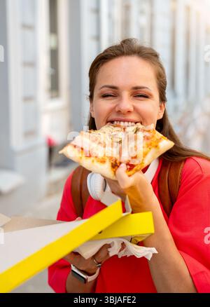 Giovane donna che si diverte con la pizza da asporto in città Foto Stock