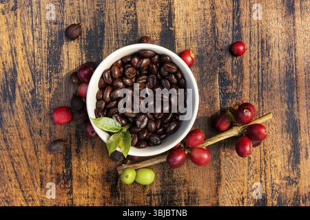 Background del caffè del commercio equo e solidale. Cofffea frutta, foglie, chicchi di caffè tostati dall'alto su sfondo di legno Foto Stock