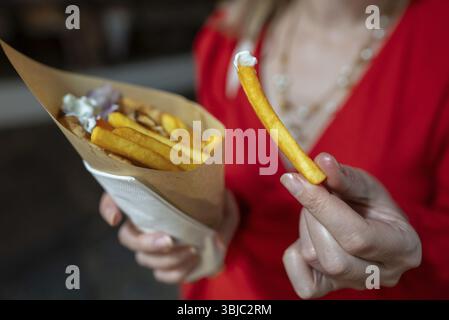 La donna mangia la pita con patatine fritte Foto Stock