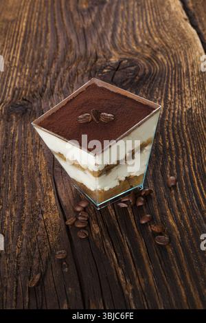 Dessert tiramisù con chicchi di caffè su un tavolo in legno. Tradizionale dessert tiramisù, rustico, in stile country Foto Stock
