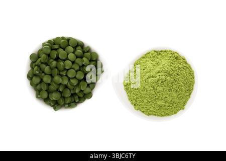 Supplemento alimentare verde. Pillole di Spirulina e impasto di erba. Pillole verdi e polvere macinata isolata su sfondo bianco, vista dall'alto. Stile di vita sano Foto Stock