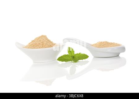Radice di Maca in polvere nella ciotola e cucchiaio isolati su sfondo bianco. Medicina alternativa, supplemento nutrizionale, organico super Foto Stock