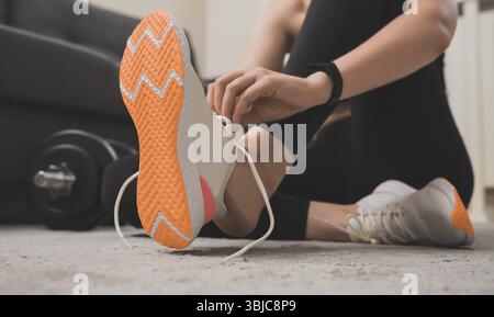 Donna che lega le scarpe prima dell'esercizio. Concetto di allenamento per il fitness a casa Foto Stock