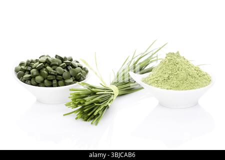 Graminacee in polvere, lame di erba di grano, spirulina e pillole di clorella isolate su sfondo bianco. Vita sana Foto Stock