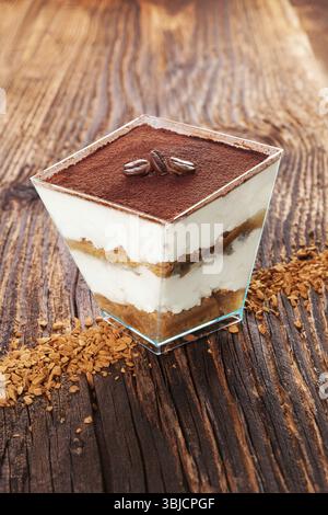 Dessert tiramisù con chicchi di caffè e caffè istantaneo su un tavolo in legno. Tradizionale dessert tiramisù, rustico, in stile country Foto Stock