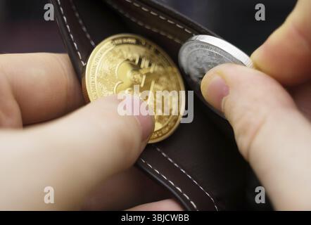 Uomo con versione fisica di bitcoin d'oro e d'argento Foto Stock
