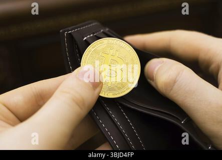 Uomo con la versione fisica del bitcoin d'oro Foto Stock