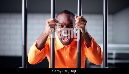 L'uniforme di Young Man in Orange Prison rinchiusa dietro le sbarre della prigione. Accusato criminale che ha scontato il mandato in cella di isolamento Foto Stock