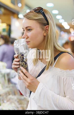 Giovane donna che sceglie le spezie nel negozio di alimentari Foto Stock