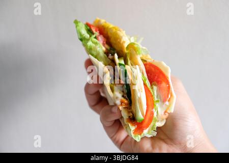 Avvolgere a mano la tortilla con pollo arrosto e vegetale Foto Stock