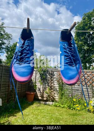 gli stivali da calcio adidas messi di colore blu pendenti formano una linea di lavaggio a londra in inghilterra Foto Stock