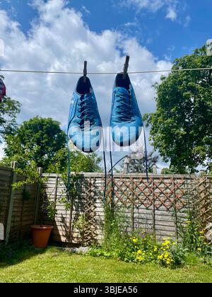 gli stivali da calcio adidas messi di colore blu pendenti formano una linea di lavaggio a londra in inghilterra Foto Stock
