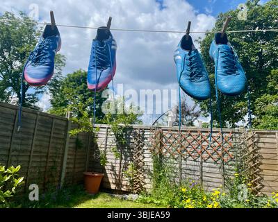 gli stivali da calcio adidas messi di colore blu pendenti formano una linea di lavaggio a londra in inghilterra Foto Stock