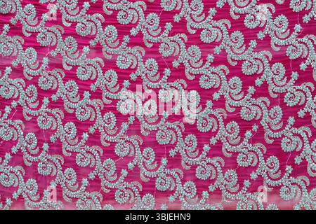 Motivo floreale su tessuto in georgette sari rosa scuro con ricami a perline. Elegante sfondo in tessuto. Foto Stock