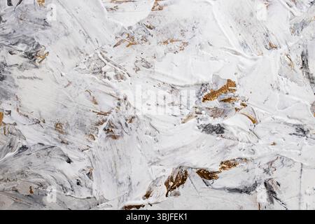 Pasta bianca di mastice mescolata con inchiostro nero, dettaglio astratto ravvicinato di colpi di spatola su ristrutturazione di stucchi di vernice dorata, Foto Stock
