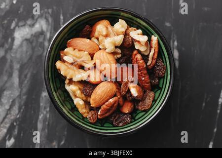 Frutta secca mista nel recipiente. Noci mandorle nocciole. Proteina sana vegana. Spuntino croccante biologico. Sfondo rustico in marmo. Immagine del cibo piatto di primo piano. Foto Stock