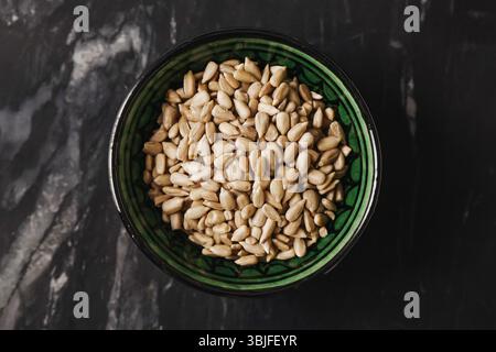 Semi di girasole sgusciati nel recipiente. Sano spuntino vegano. Cibo vegetale biologico. Consistenza naturale dei semi. Vista di primo piano. Foto Stock