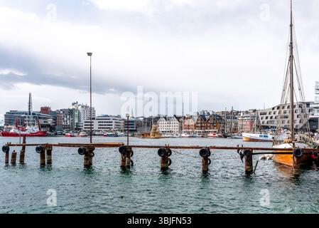 Tromso, Norvegia, 05.13.2025. Edifici incantevoli, barche a vela, yacht e barche da pesca nel porto in una nuvolosa giornata primaverile. Paesaggio urbano di Tromso Foto Stock