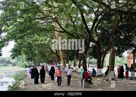 I visitatori passeggiano sotto gli alberi lungo lo stagno di Ghora dighi vicino alla storica Moschea Sixty Dome a Bagerhat, Bangladesh. Foto Stock