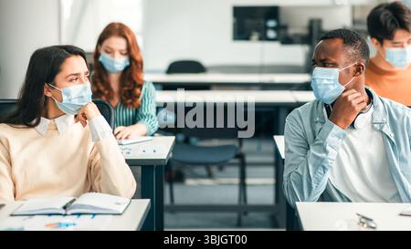 Studenti internazionali che indossano maschere mediche e parlano Foto Stock