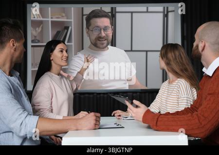 Gruppo di persone che partecipano a una conferenza aziendale al chiuso. Altoparlante sullo schermo di proiezione Foto Stock