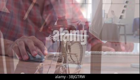 Mani di un uomo che muove il mouse e digita la tastiera sulla scrivania dell'ufficio, con bicicletta, tazza da caffè Foto Stock