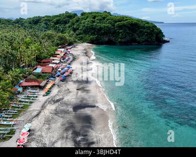 Vista aerea del drone, la spiaggia vergine di Karangasem, Bali, sembra una foresta e un oceano blu e lungo la spiaggia c'è sabbia bianca nera Foto Stock
