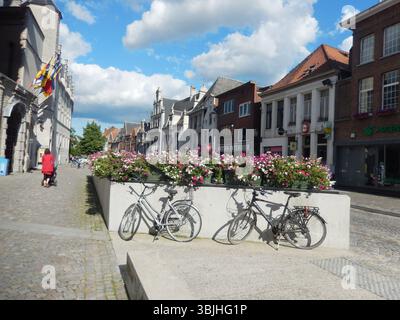 Affascinante strada europea con biciclette e fiori colorati in una giornata di sole. Mechelen, Belgio Foto Stock