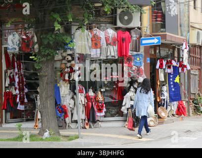 Prizren, Kosovo-30 maggio 2025: Donna non identificata che cammina nel negozio di costumi tradizionali del Kosovo e magliette patriottiche Foto Stock