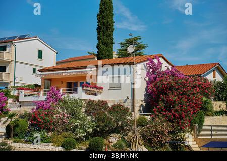 Casa bianca mediterranea con grande balcone e giardino fiorito. Villa bianca con fiori vicino alla costa adriatica. Architettura costiera in Croazia Foto Stock