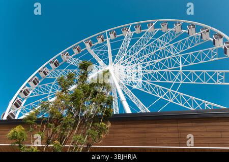 Primo piano della ruota panoramica contro Clear Blue Sky. Una vista ravvicinata di una ruota panoramica bianca adagiata su un cielo blu limpido, che ne mette in risalto la complessità Foto Stock