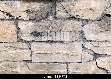 Struttura muraria in pietra ruvida con blocchi irregolari. Vista ravvicinata di un muro di pietra grezza composto da blocchi di forma irregolare che mostrano texture naturali Foto Stock