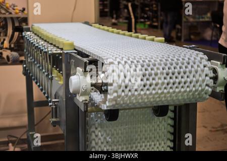 Primo piano del nastro trasportatore modulare in plastica bianco su macchinari per l'automazione industriale. Evidenziando la struttura e i componenti del nastro in fabbrica o in loghi Foto Stock
