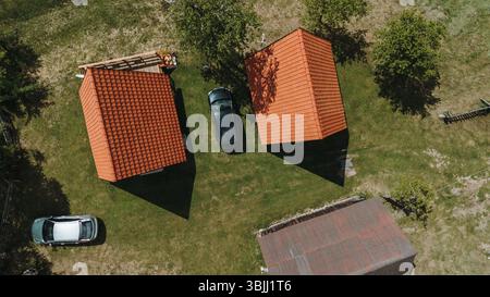 Vista aerea dall'alto di due cabine con tetto rosso e auto parcheggiate sull'erba verde nel Parco Nazionale di Tara, in Serbia, nella stagione primaverile. Foto Stock