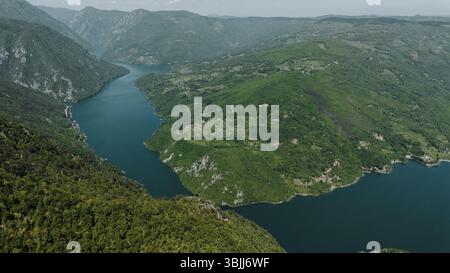 Vista aerea del tortuoso lago Perucac che si estende tra ripide montagne verdi nella Serbia occidentale, mostrando una bellezza naturale incontaminata. Tara National Foto Stock