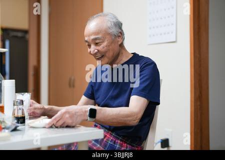 In un piccolo appartamento giapponese, un uomo giapponese alla fine degli anni '70 si rilassa in pigiama T-shirt. Si siede da solo la sera, sorseggiando whisky e godendosi un Foto Stock