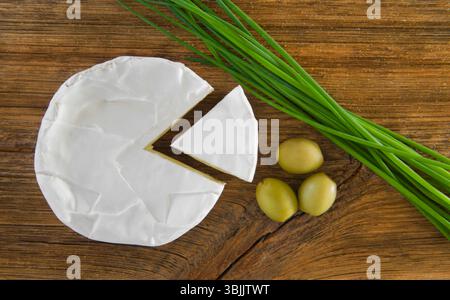 Formaggio camembert, olive e cipolla verde su un vecchio tavolo di legno. Vista dall'alto Foto Stock