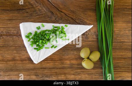 Formaggio camembert, olive e cipolla verde su un vecchio tavolo di legno. Vista dall'alto Foto Stock