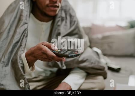 Guardare la televisione tenendo il telecomando in mano Foto Stock